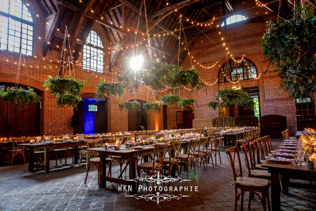 Décoration de mariage dans la salle des Écuries de Rivaulde, avec des arrangements floraux et une ambiance chaleureuse créée par des bougies et des guirlandes lumineuses.